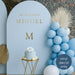 Minimalist gold vinyl decal “Mi Bautizo Miguel” with initial “M” on light blue backdrop for baptism celebration decoration